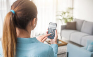 smart thermostat - woman using smart phone app to operate her HVAC unit